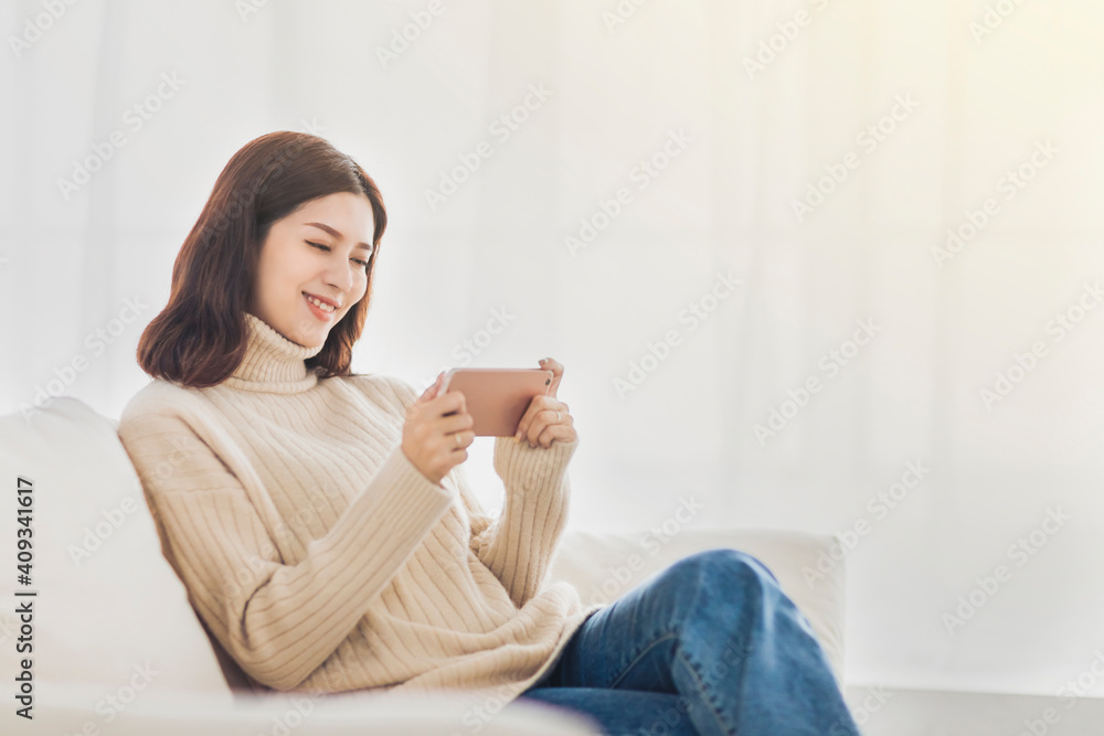 Happy young woman relaxing on couch and watching the mobile phone Happy young woman relaxing on couch and watching the mobile phone