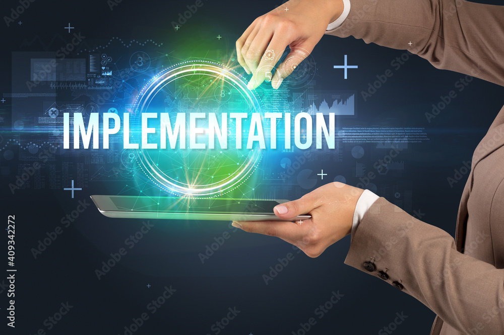 Close-up of a touchscreen with IMPLEMENTATION inscription, new technology concept
