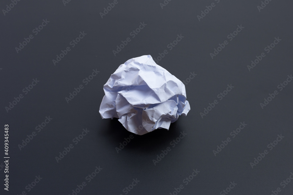 Crumpled white paper ball on dark background.