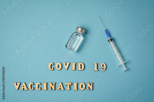 Inscription covid 19 vaccination, vaccine, syringe lie on blue background