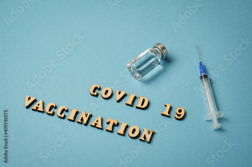 Text covid 19 vaccination, vaccine, syringe lie on blue background