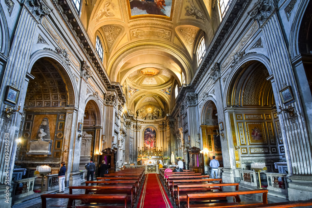 Visitors appreciate the gothic church interior apse, arches and naves of the basilica of Santi Vincenzo e Anastasio a Trevi in the historic center of Rome, Italy.