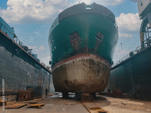 Industry view - Ocean Vessel in the dry dock in shipyard. Old rusty ship under repair. View from forward