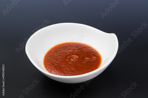 Red Souce in white dish on black, dark background