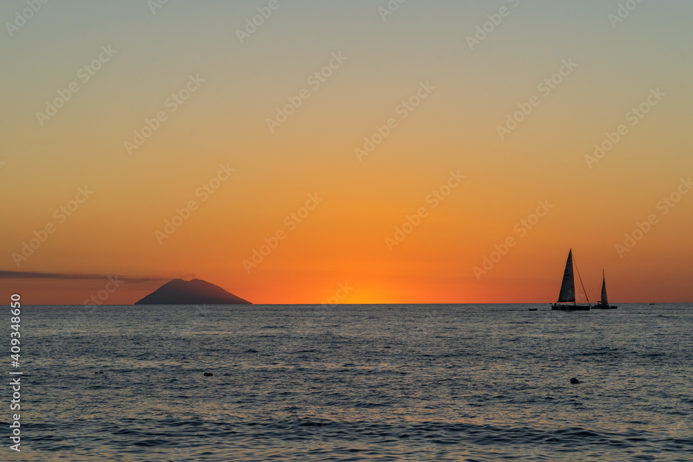 Beautiful sunset over Tyrrhenian Sea and Stromboli island with a sailboat viewed from Tropea, Calabria, Italy