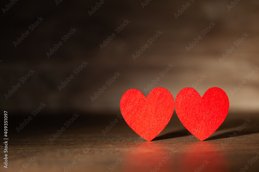 Fototapeta premium Against the background of a dark tree two red hearts, use as a background or postcard
