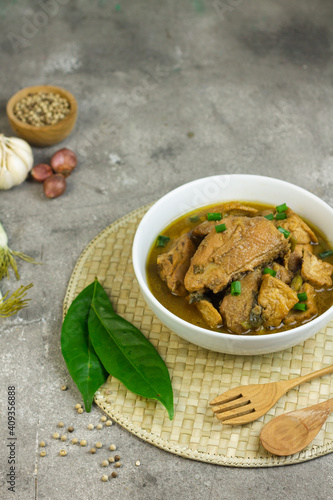 Semur Ayam Tahu, Indonesian traditional food made with chicken, tofu, spices, soy sauce and palm sugar. Grey grainy background, copy space for text. 