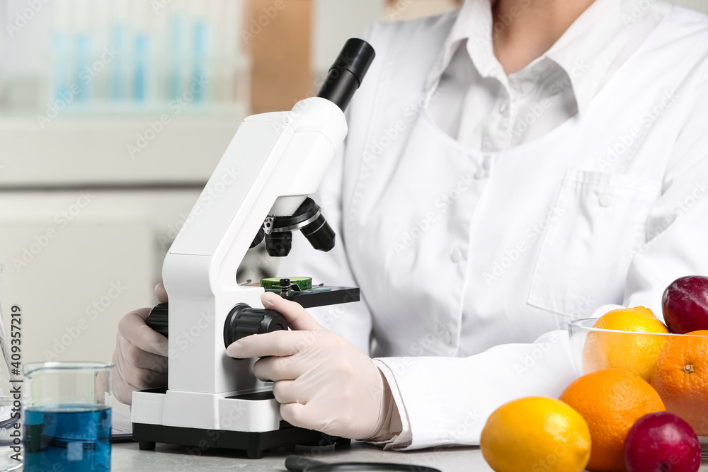 Scientist inspecting slice of cucumber with microscope in laboratory, closeup. Poison detection Scientist inspecting slice of cucumber with microscope in laboratory, closeup. Poison detection