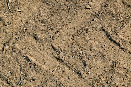 Tractor tire tracks on dirty sand, abstract background, textural material, retro, grunge.