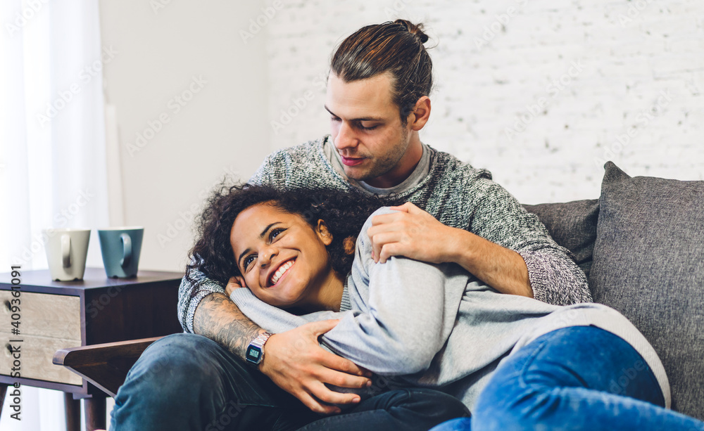 Romantic young happy love couple caucasian man and african american woman smile and have fun hugging together in valentine day on the bed at home Romantic young happy love couple caucasian man and african american woman smile and have fun hugging together in valentine day on the bed at home