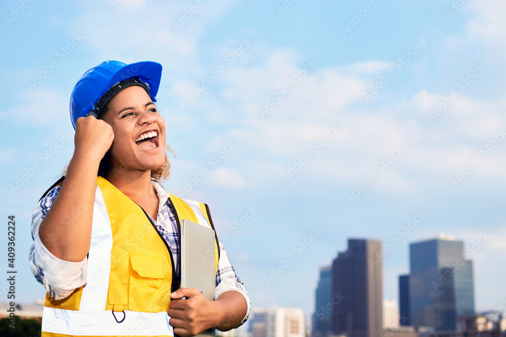 Portrait of African American woman architect wearing a vest and helmet in urban.