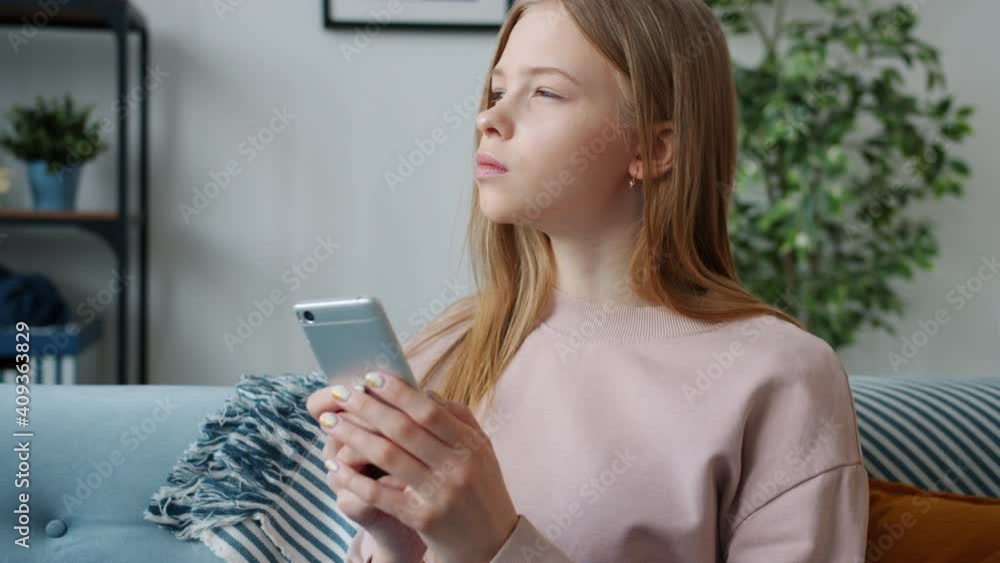 Slow motion of serious teen child using smartphone messaging indoors in apartment. Online communication and modern technology for children concept. Slow motion of serious teen child using smartphone messaging indoors in apartment. Online communication and modern technology for children concept.