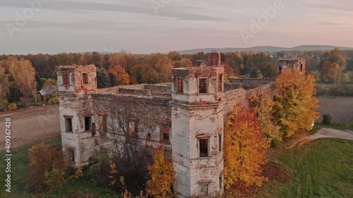 Drone aerial shot of old castle ruins located in Poland in beautiful autumn scenery with colourful trees and sunset sky