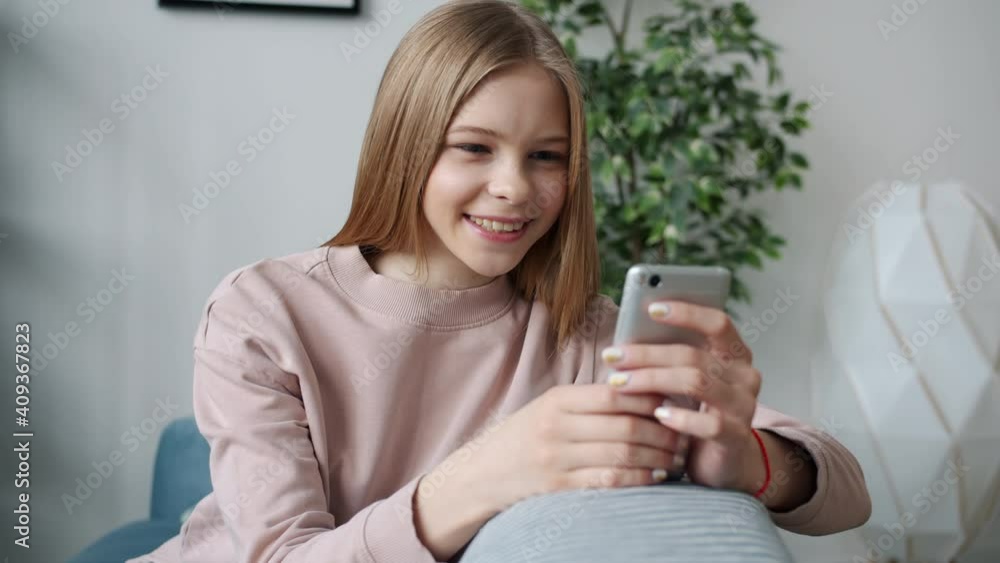 Slow motion of happy kid using smart phone at home smiling swiping enjoying internet content alone. Contemporary devices and teenagers concept. Slow motion of happy kid using smart phone at home smiling swiping enjoying internet content alone. Contemporary devices and teenagers concept.