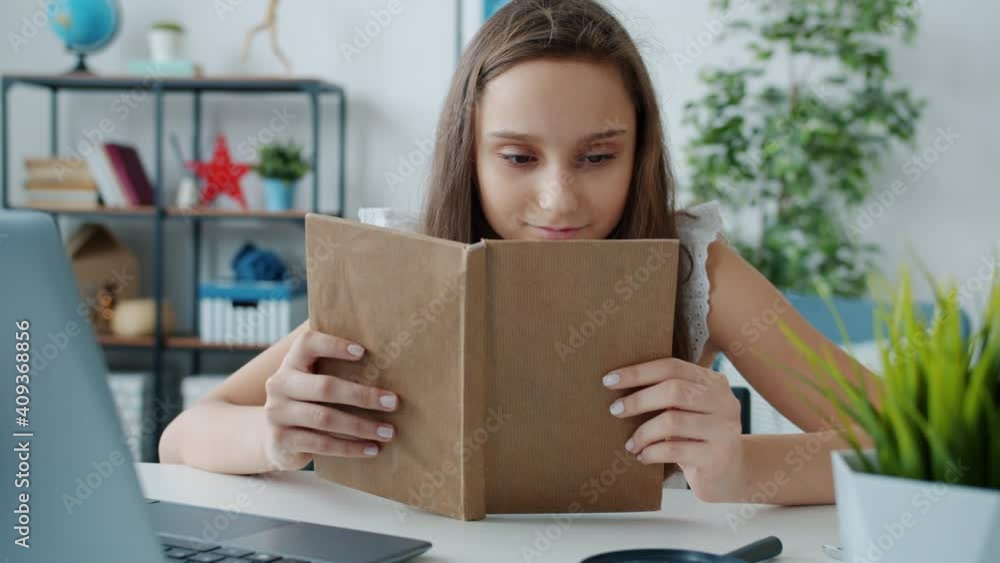 Slow motion of child reading interesting book and smiling enjoying funny story sitting at table at home. Intelligent young people and hobby concept. Slow motion of child reading interesting book and smiling enjoying funny story sitting at table at home. Intelligent young people and hobby concept.