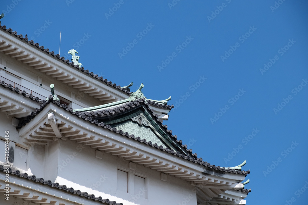 Wakayama, Wakayama Prefecture / Japan, October 15 2020: Close-up low angle view of Wakayama Castle tiled roof and a clear blue sky.