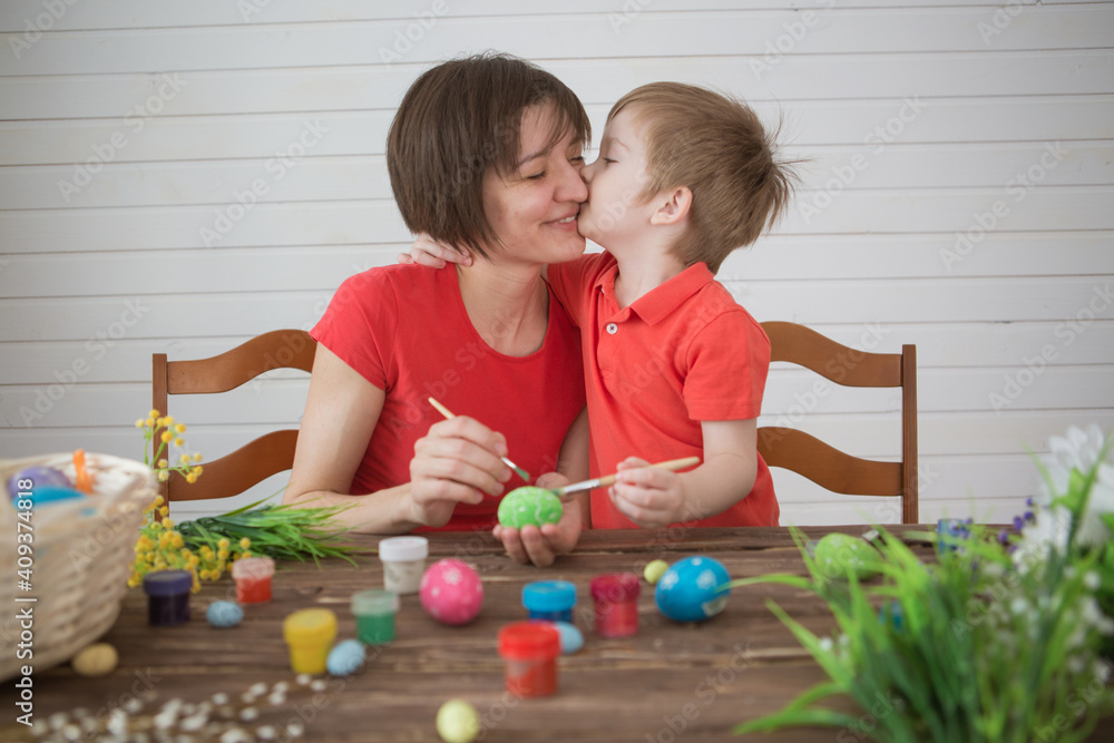 Naklejka premium Mother and her son painting Easter eggs. Happy family preparing for Easter day