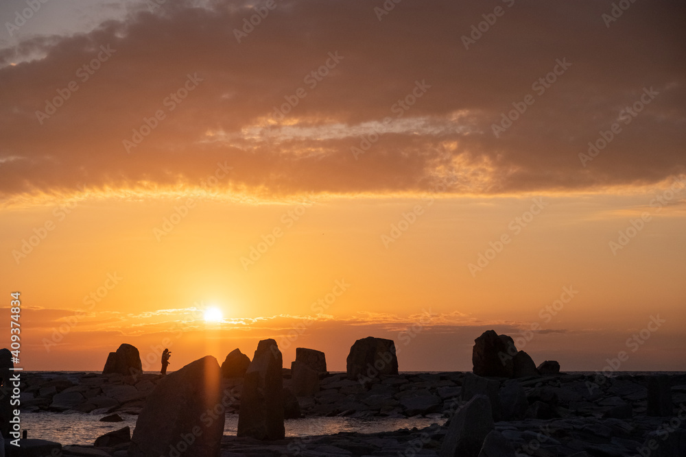 Cloudy sunset with silhouette of person standing on a rocky shore at Shirahama Beach in Wakayama Prefecture, Japan