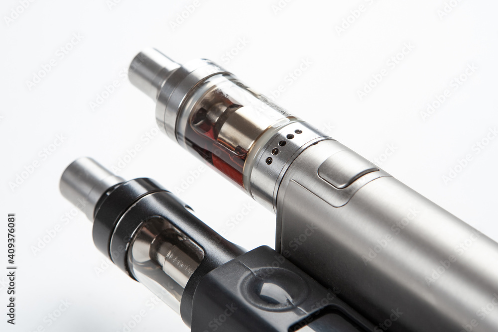 Two Electronic Cigarette close-up. Fragment of Electronic Cigarette on a white background. Vaping cigarettes. Devices for smoking steam. Cigarettes are modern. Concept devices from vape shop Two Electronic Cigarette close-up. Fragment of Electronic Cigarette on a white background. Vaping cigarettes. Devices for smoking steam. Cigarettes are modern. Concept devices from vape shop