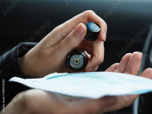 woman dripping essential oil on a medical mask while driving a car