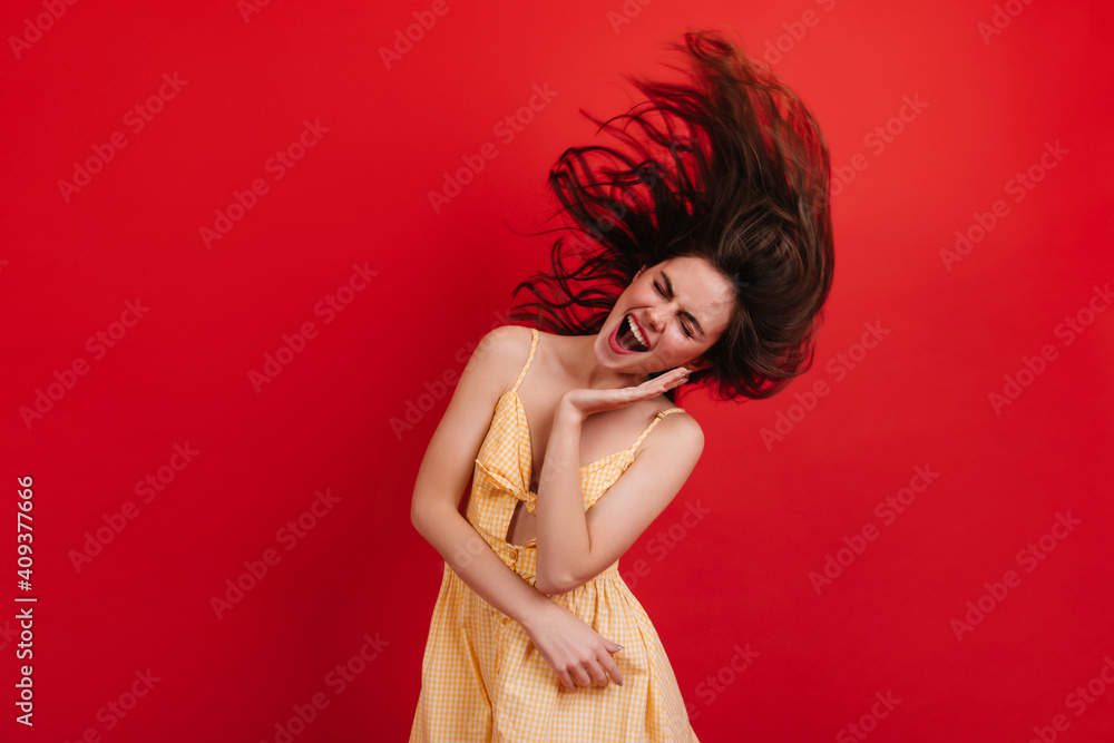 Screaming girl dances and plays with hair. Woman in summer outfit posing emotionally on red background Screaming girl dances and plays with hair. Woman in summer outfit posing emotionally on red background