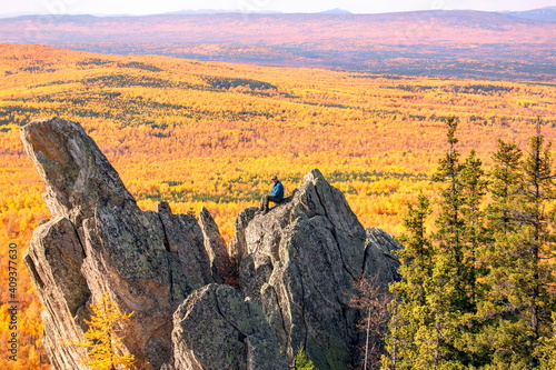 mature tourist posing on the rocks of the mountain round hill on the Alabiya ridge in the Ural mountains on an autumn sunny day. photo