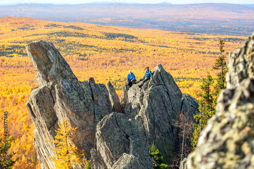 mature tourist posing on the rocks of the mountain round hill on the Alabiya ridge in the Ural mountains on an autumn sunny day. photo