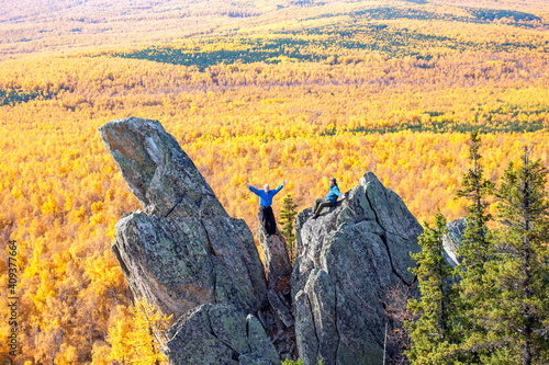 Mature tourists posing on the rocks of the mountain round hill on the Alabia ridge in the Ural mountains on an autumn sunny day. photo