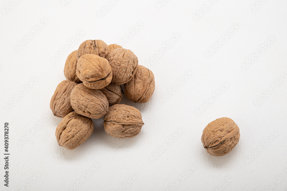 Unpeeled walnuts in a shell on a light background Unpeeled walnuts in a shell on a light background