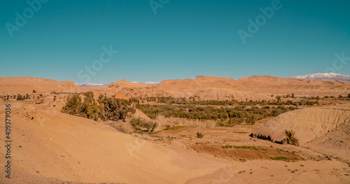 Panorama view of desert and clay houses and the Kasbah (fortress) in the ancient town of Aid Benhaddou, Morocco with Atlas mountains in the background