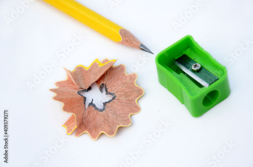 the yellow wooden peels pencil with sharpener and waste flower isolated on white background.