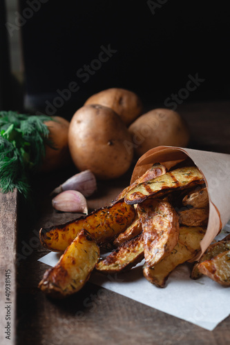 Delicious baked country potatoes with spices, dill and green onions, on a wooden table