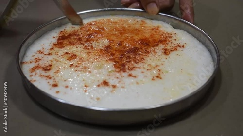 Cutting white dhokla also known as khaman in symmetrical square shape with hands, Gujrati dish made of white batter photo