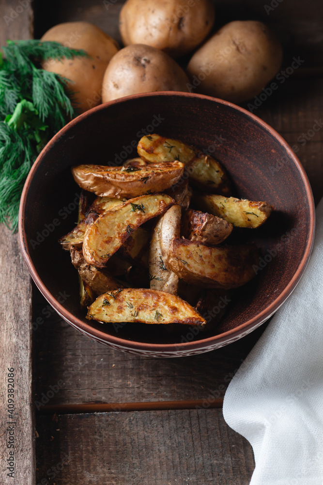 Delicious baked country potatoes in a earthen bowl with spices, dill and green onions, on a wooden table Delicious baked country potatoes in a earthen bowl with spices, dill and green onions, on a wooden table
