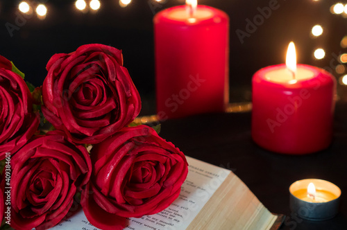 Red rose on book and candles for romantic valentine night.