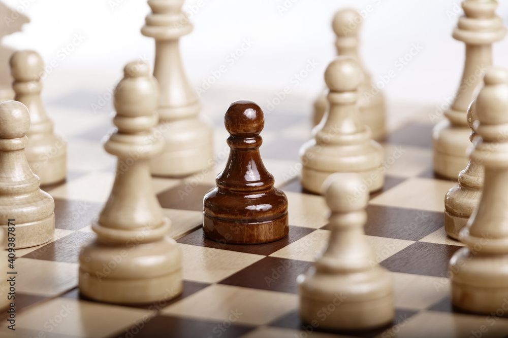 Black pawn standing among white chess figures Black pawn standing among white chess figures
