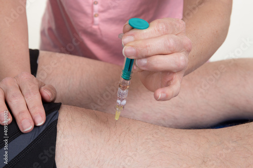Man getting vaccine injection in the thigh by a female doctor