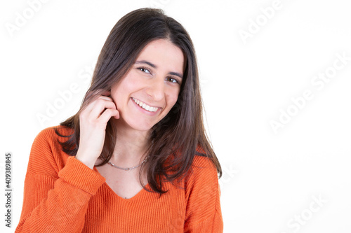 Portrait of happy smiling young beautiful woman isolated over white background looking at camera hand on hair