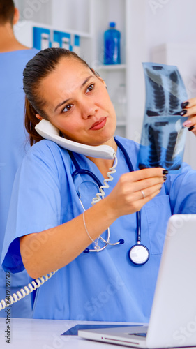 Physician nurse answering patient call by phone, looking at his radiographys, mri scan. Healthcare physician in medicine uniform, receptionist doctor assistant helping with phone concultation