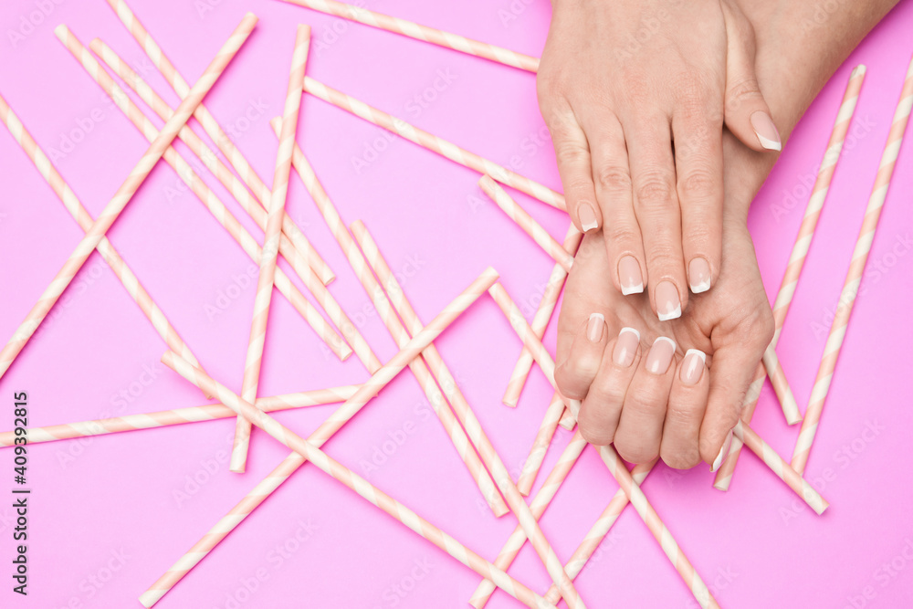Fototapeta Beautiful Female Hands with French manicure over colorful paper background