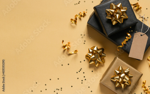 Gift boxes with golden bows, ribbons and stars on yellow background. Copy space for your text. Flat lay, top view 
