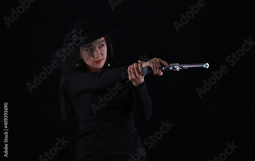 portrait of a sexy girl killer with a gun on a black background