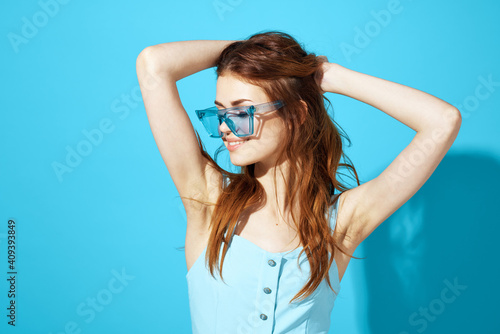 cheerful pretty woman holding blue glasses dress by her hair cropped view Studio