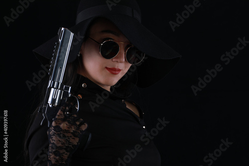 portrait of a sexy girl killer with a gun on a black background