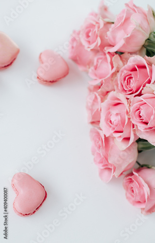 Pink roses on a white surface with pink heart shaped macaroons for life event