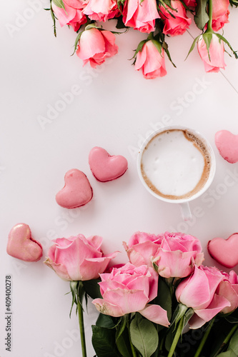Coffee cup on a empty surface with a heart shaped macaroon, pink roses