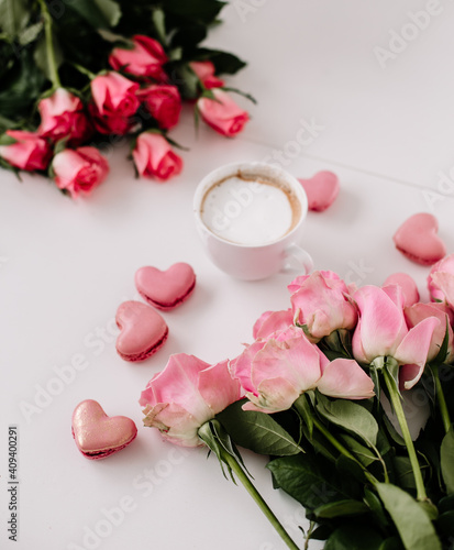 Coffee cup on a empty surface with a heart shaped macaroon, pink vibes with roses