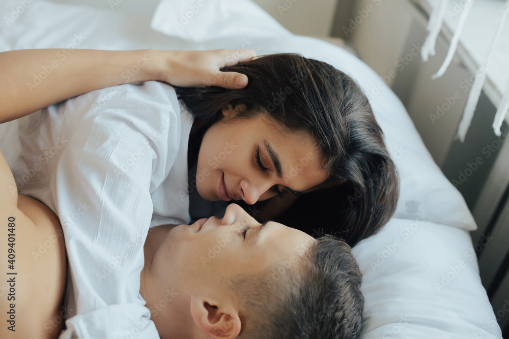 Happy loving couple resting on the bed at home and stroking, affection, enjoying unity and tenderness. Close up.