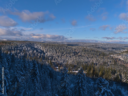 Stunning panoramic view over Black Forest mountain range near Kniebis, Freudenstadt, Germany with snow-covered forest on the hills in light and shadow on sunny day in winter season with blue sky.