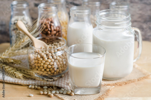 Closed up fresh organic soybean milk in glass bottle with fresh seeds on wooden background